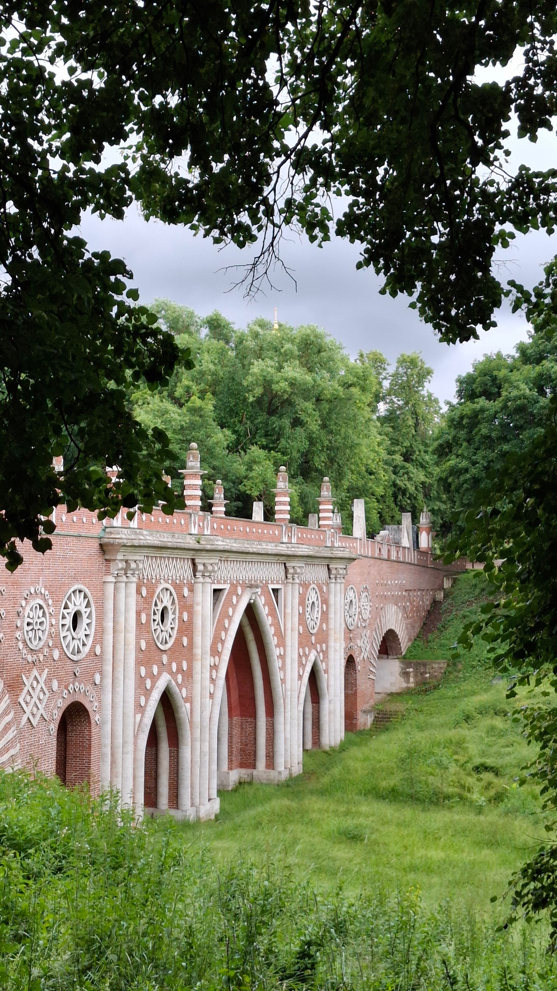 Beautiful Gothic-style brick bridge in lush greenery, perfect for travel and architecture themes.