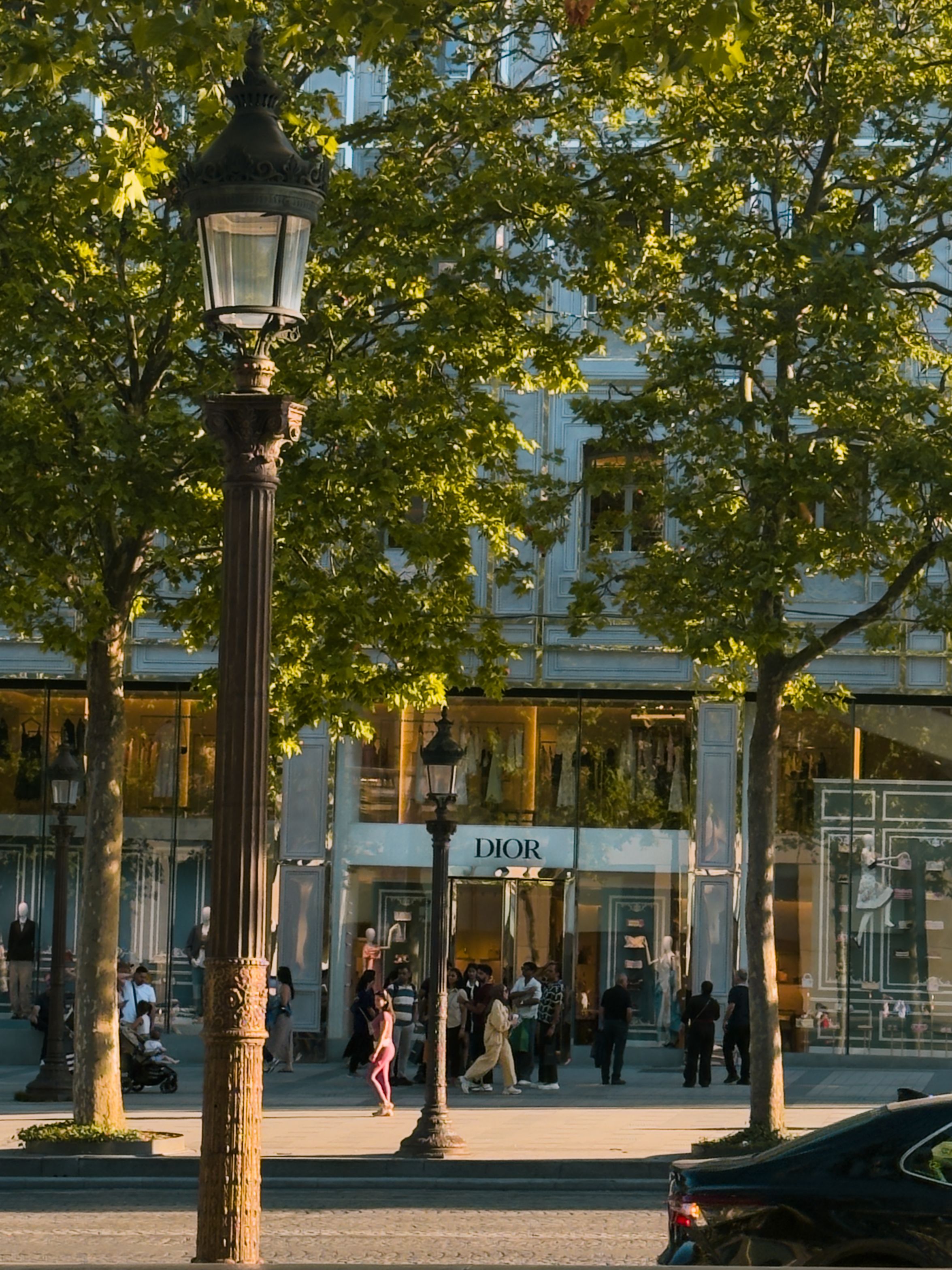 Bustling Paris street with the Dior boutique at sunset, capturing city life.