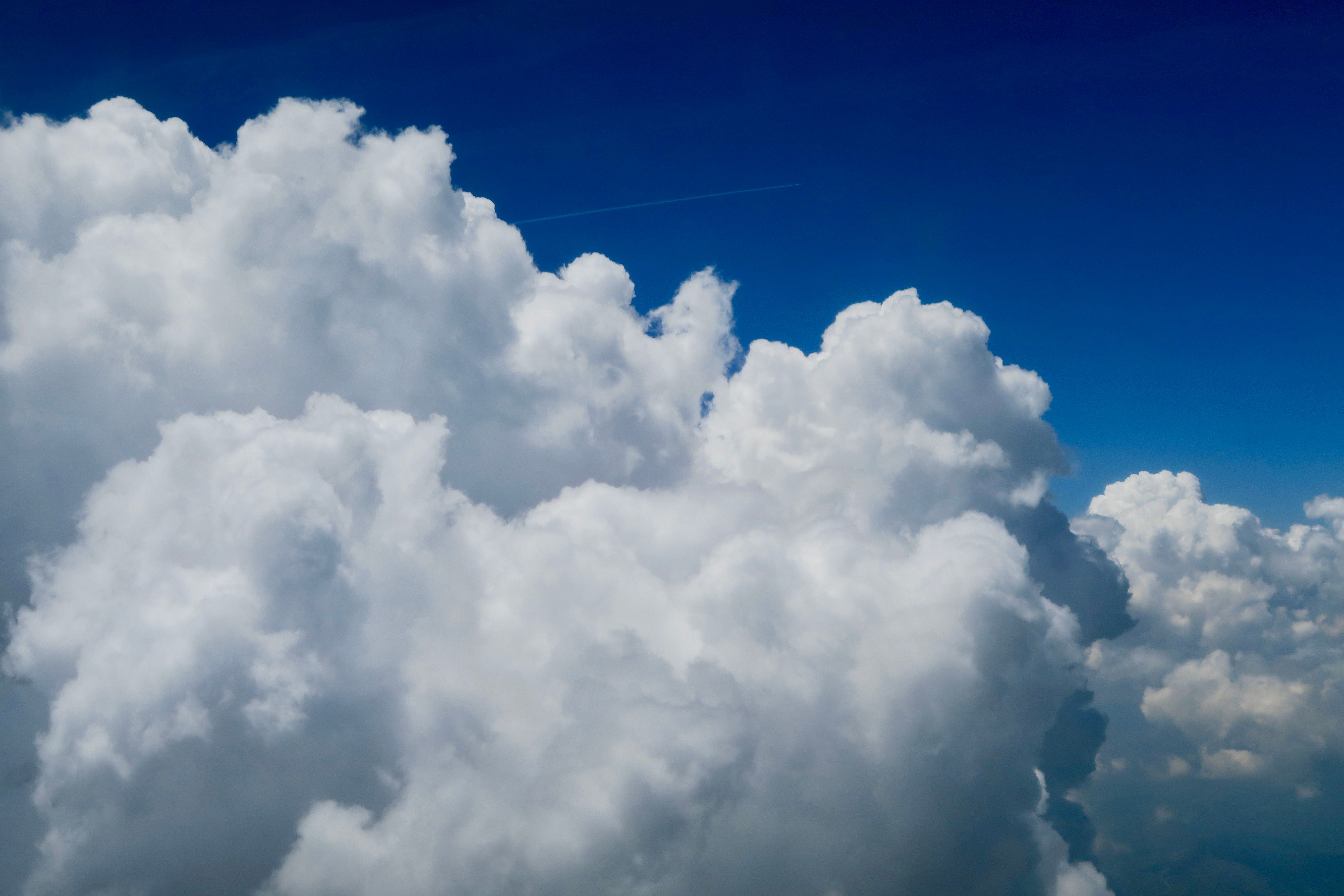 Aerial view of fluffy cumulus clouds under a vivid blue sky, representing serenity and natural beauty.
