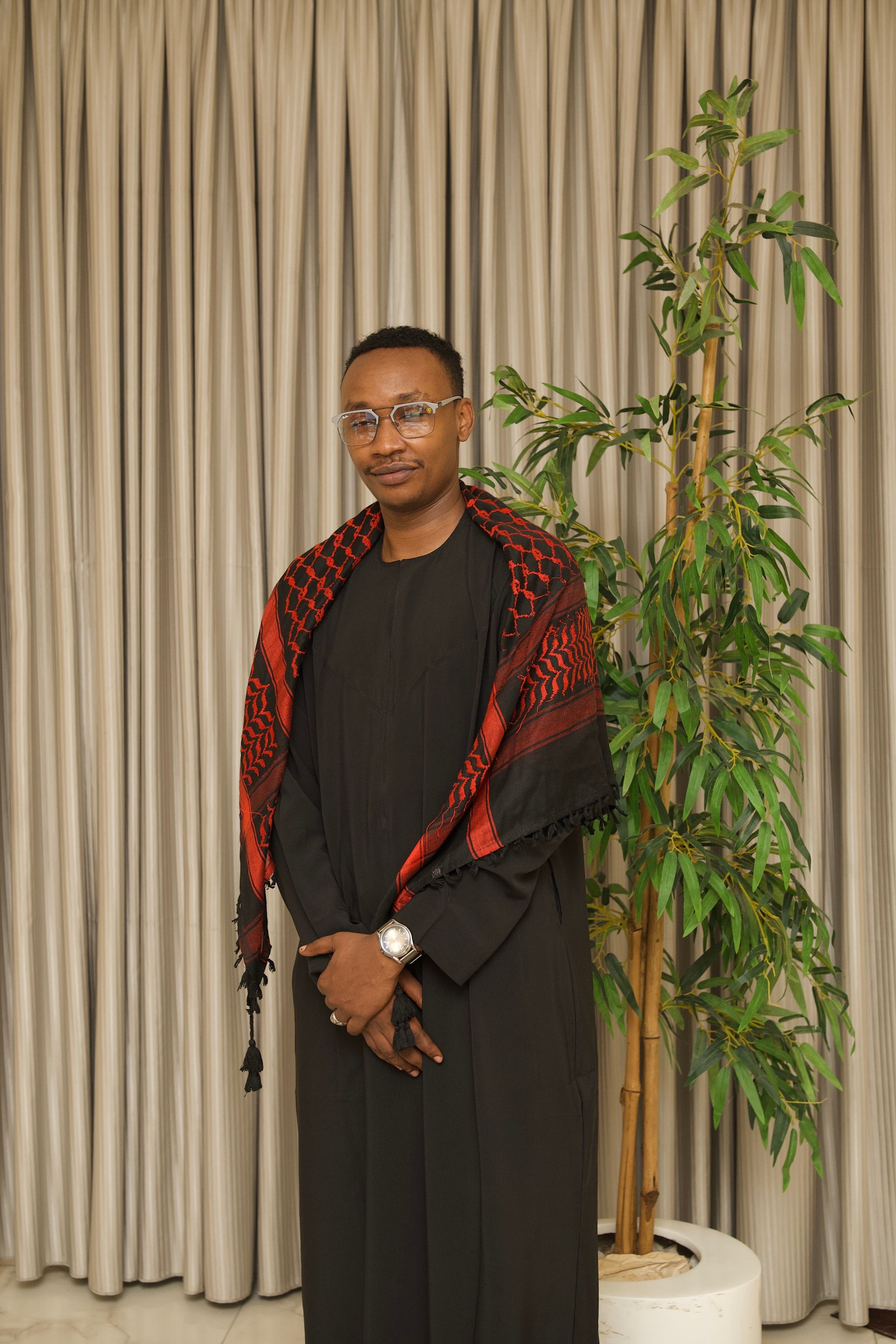 Elegant portrait of a man in traditional attire with a minimalist indoor setup, showcasing sophistication and cultural pride.
