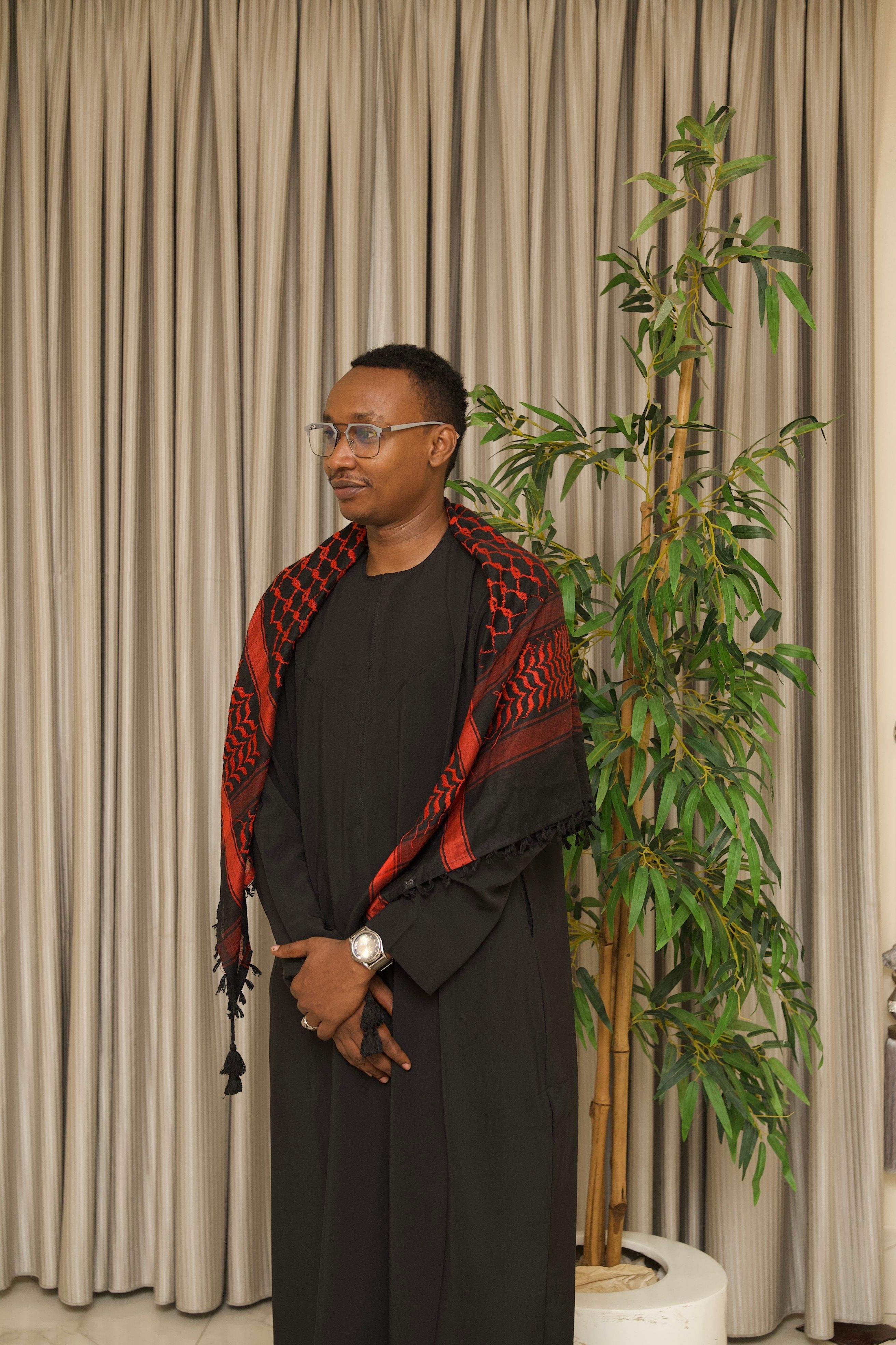 Stylish portrait of a man in traditional attire with indoor greenery.