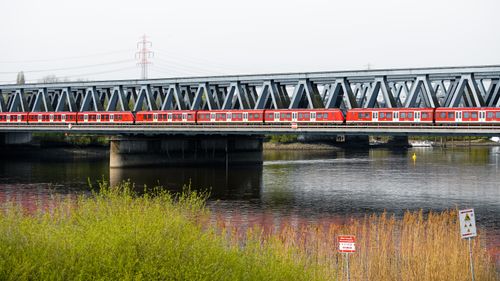 Free A vibrant red commuter train crosses the Elbbrücken railway bridge in Hamburg, Germany. Stock Photo