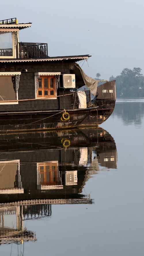 Free Traditional houseboat reflecting on calm waters, showcasing serene and tranquil setting. Stock Photo