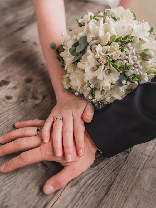 Photo of Hands With Wedding Rings and Bridal Bouquet