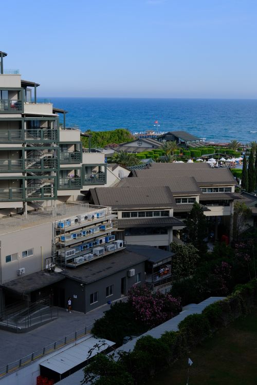 Free Modern coastal hotel overlooking the blue ocean under a clear sky. Stock Photo