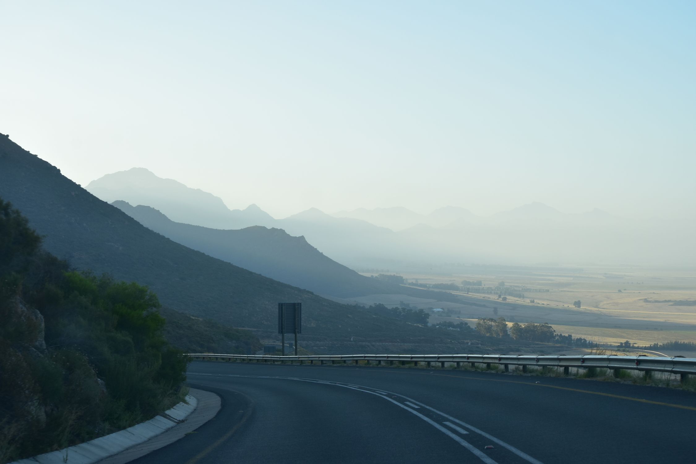 A serene view of a winding highway surrounded by mountains at dawn in South Africa.