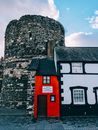 Facade of small house and masonry tower under cloudy sky
