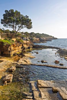 Stunning coastal view of rocky shoreline and clear water in S'Arenal, Islas Baleares, Spain.