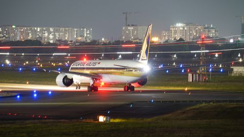 Free A Singapore Airlines plane on the runway at night amidst city lights and airport lights. Stock Photo