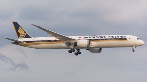Free A Singapore Airlines Boeing 787 is captured mid-flight with landing gear extended against a cloudy sky. Stock Photo