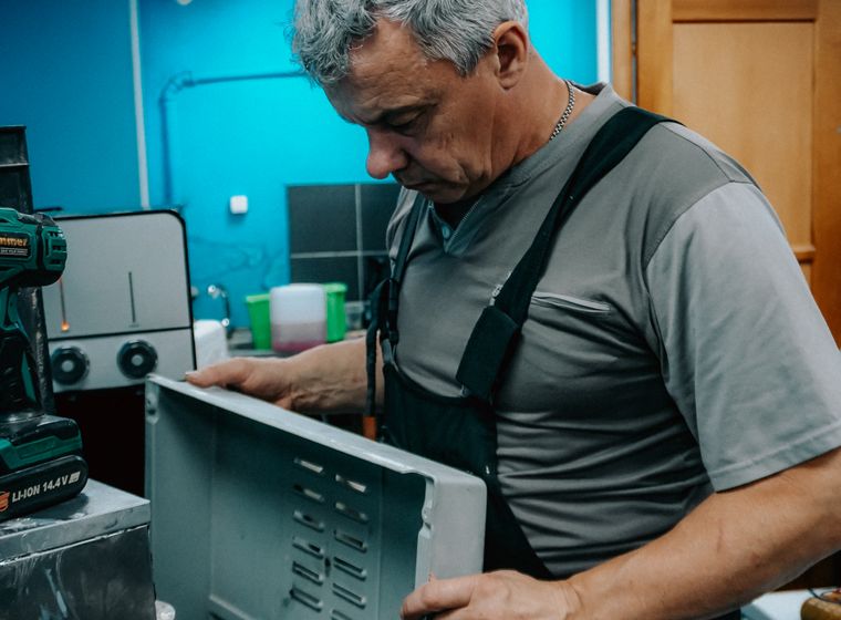 Repair technician examining a home appliance indoors