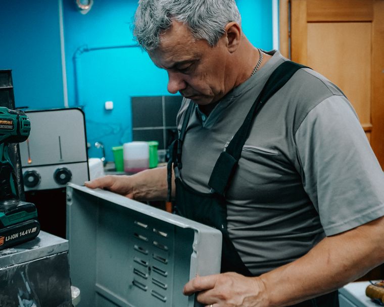 Honest in home appliance repair Technician examining a home appliance during an in home repair visit