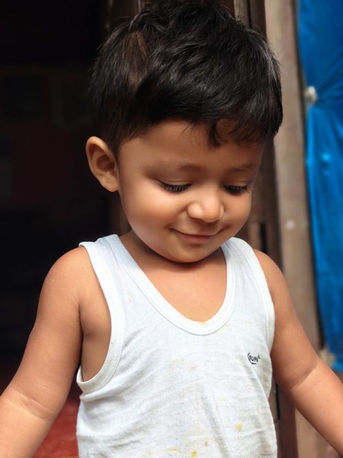 Free Cute toddler smiling outdoors in casual white tank top under natural sunlight. Stock Photo