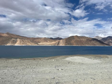 Breathtaking vista of Pangong Lake with Himalayan mountains under a striking sky.