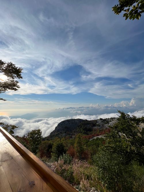 Free Stunning view of Montenegro mountains with clouds below and a wooden railing in the foreground. Stock Photo
