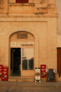 A cozy European café entrance with vintage charm and menu boards outside, inviting atmosphere.