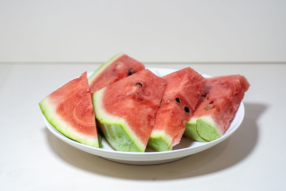Juicy watermelon slices arranged on a white plate against a plain background.