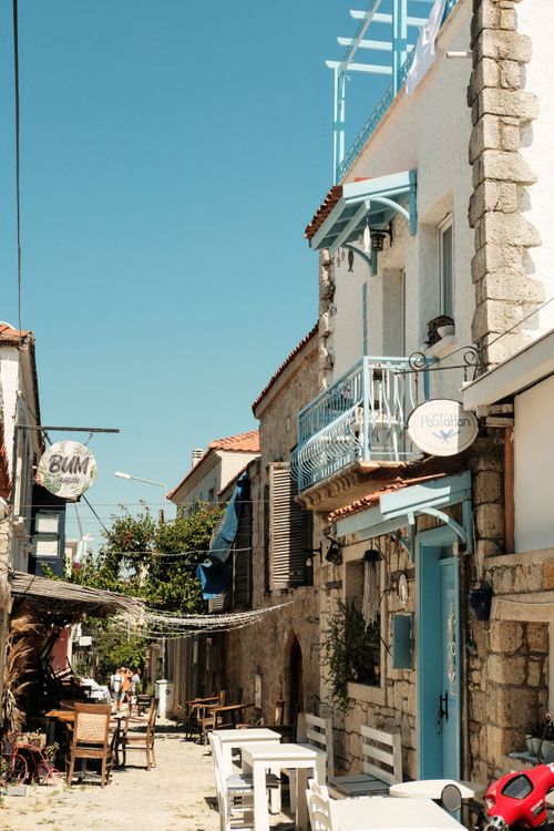 Free Sunlit charming street in a Mediterranean village with outdoor cafes and local architecture. Stock Photo