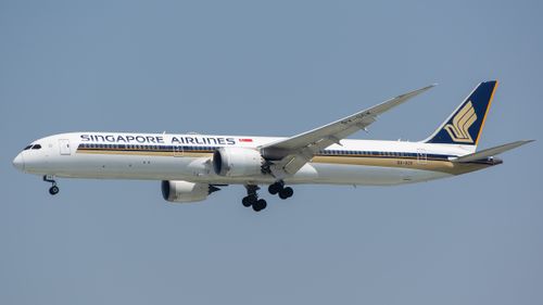 Free Singapore Airlines Boeing 787 Dreamliner flying against a clear blue sky. Stock Photo