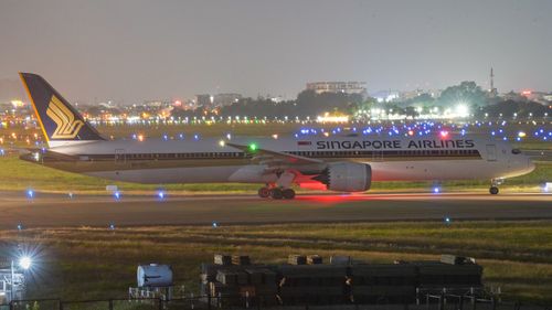 Free Singapore Airlines airplane on runway at night, airport lights glowing. Stock Photo