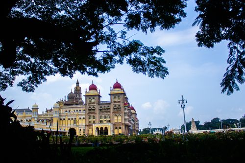 Free Stunning view of Mysore Palace framed by lush trees, capturing its opulent architecture. Stock Photo