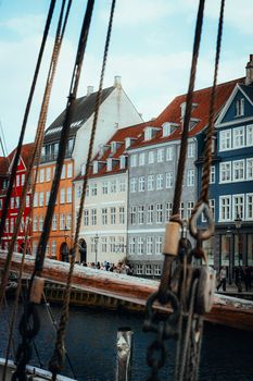 Scenic view of colorful buildings along Nyhavn waterfront in Copenhagen with sailing ropes in the foreground.