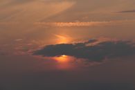 Stunning sunset scene with dark clouds and vibrant orange hues in the sky.