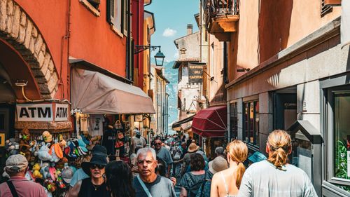 Free Lively street in Malcesine, Italy, showcasing vibrant architecture and bustling tourists. Stock Photo