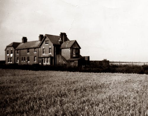 Grayscale Photo of House on Grass Field