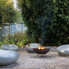 A cast iron fire bowl on legs in a garden patio