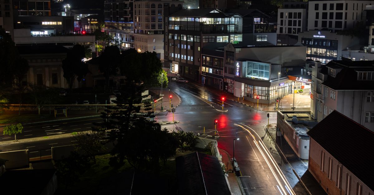 A vivid nighttime urban scene showcasing illuminated buildings and captivating light trails on wet streets.