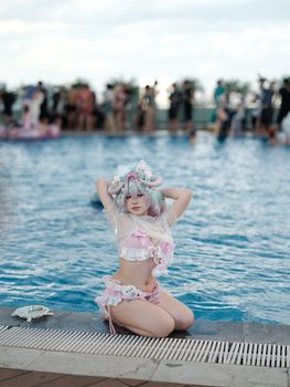 Girl in pastel cosplay poses by the poolside on a sunny day, colorful and vibrant.