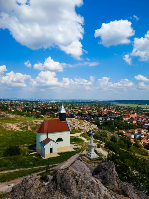 Free Aerial view of Budaörs, Hungary with a small church and cross under a bright blue sky. Stock Photo