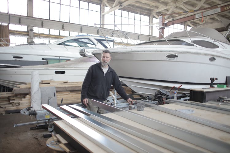 Male Master In Hangar With Motor Boats