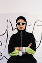 室内现代艺术氛围中，一位戴着头巾和时尚太阳镜的自信女性肖像
