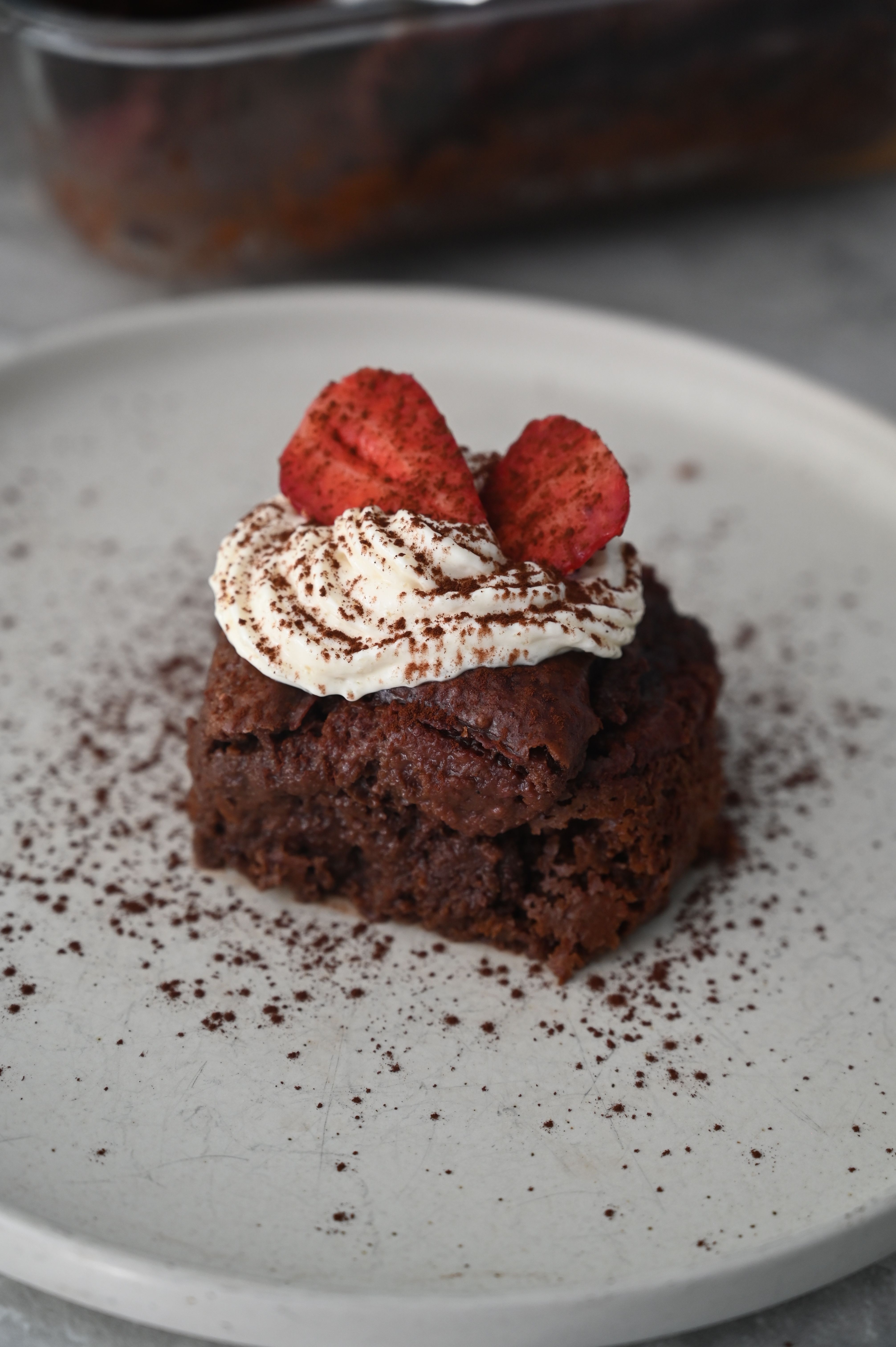 A two-layer vegan chocolate cake covered in glossy chocolate ganache that drips down the sides, sliced to reveal a moist, dark crumb.