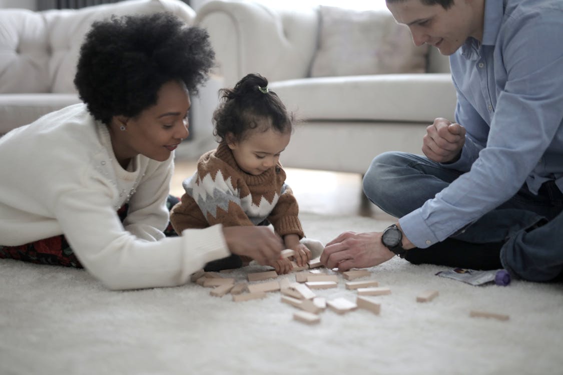 Photo of Man and Woman Playing With Their Child