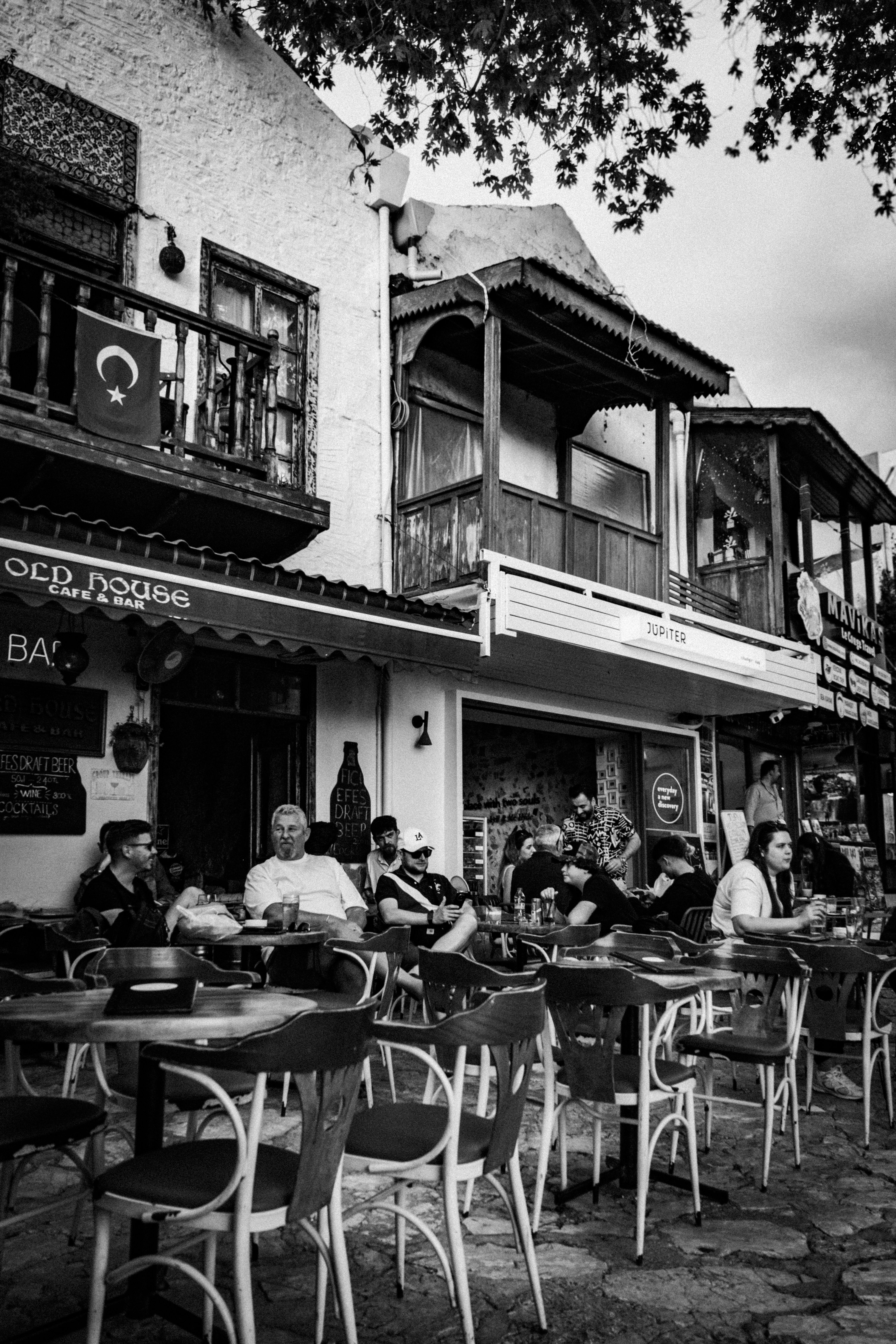 Lively street café scene with a Turkish flag and patrons enjoying a casual day in Bodrum.