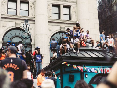 Free Crowd of diverse adults gathered on a rooftop in a vibrant city setting, celebrating with flags. Stock Photo