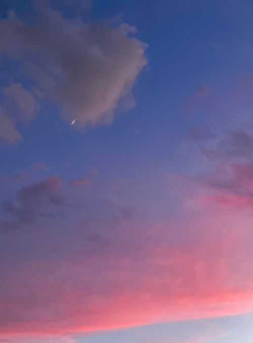 Free A serene evening sky featuring a crescent moon with pink and blue clouds. Stock Photo