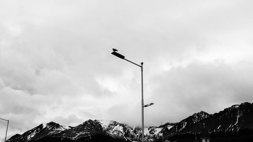 Free Black and white image of a streetlamp against dramatic mountains and clouds in Ushuaia, Argentina. Stock Photo