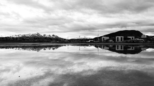 Black and white landscape of Ushuaia with mountain reflections in water.
