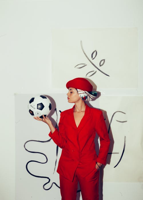 Mulher De Blazer Vermelho Segurando Uma Bola De Futebol Preta E Branca