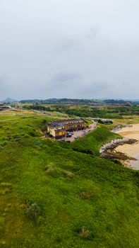 A vibrant coastal landscape featuring lush greenery and a sandy beach in Asturias, Spain.