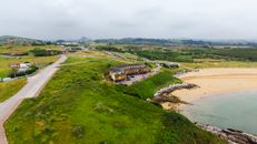 Aerial view of the green coastline and sandy beach in San Vicente de la Barquera, Cantabria, Spain.