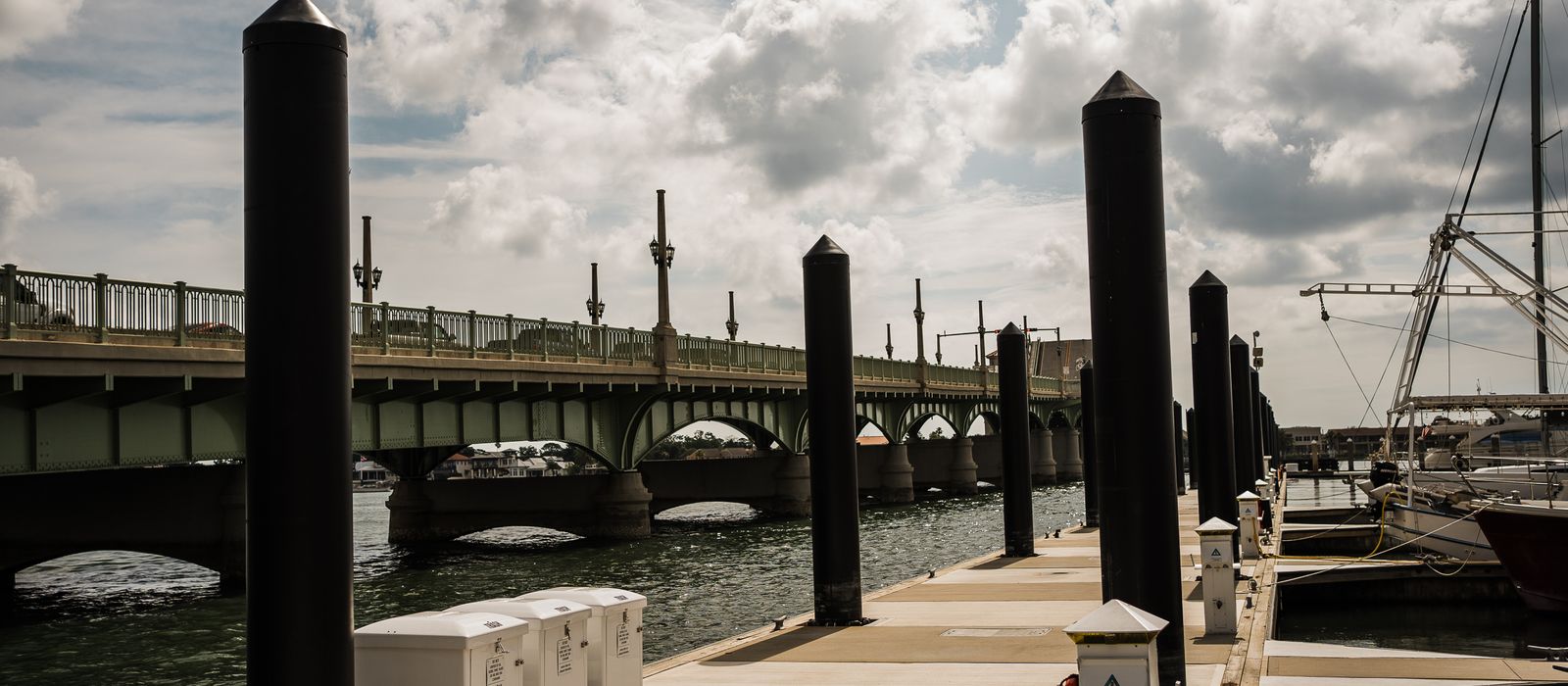 View of St. Augustine's iconic bridge and marina on a sunny day with scattered clouds.