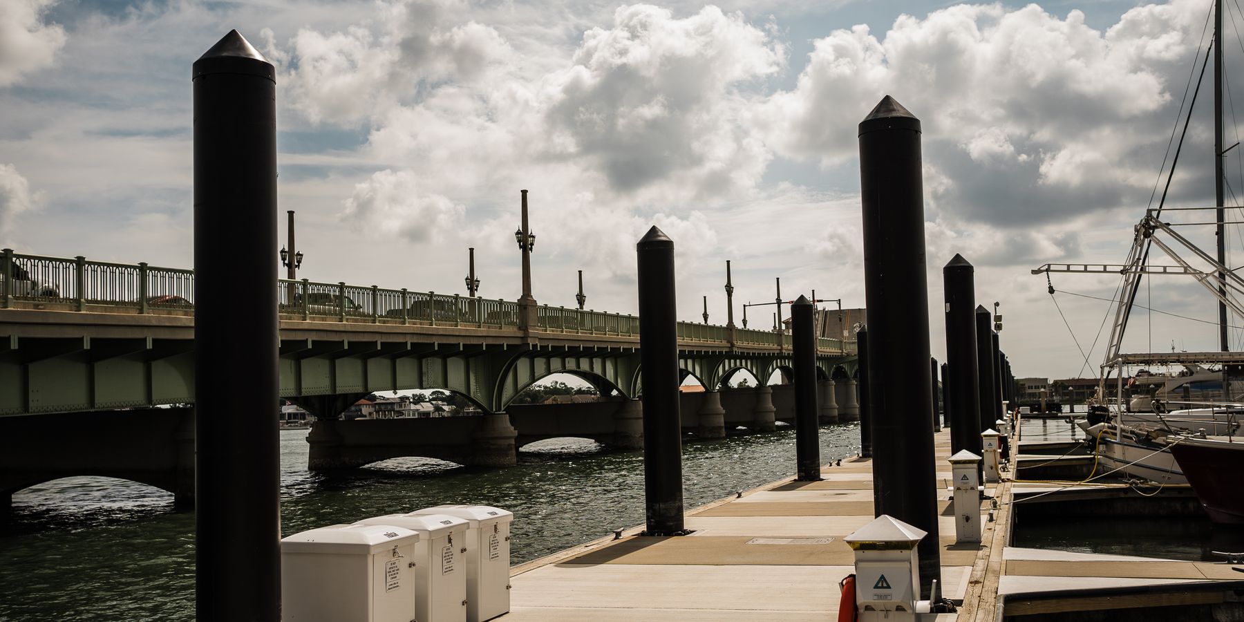 View of St. Augustine's iconic bridge and marina on a sunny day with scattered clouds.