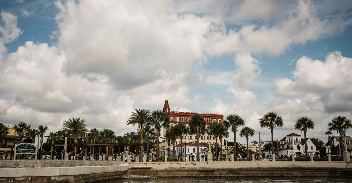 Picturesque view of St. Augustine waterfront with palm trees and historic architecture under cloudy skies.