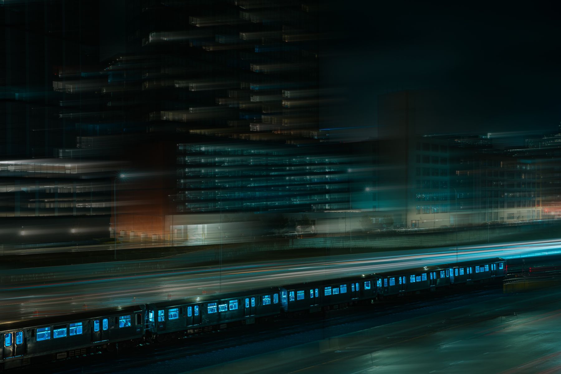 Night train streaking past lit towers, long exposure &mdash; photo by Roy Serafin on Pexels