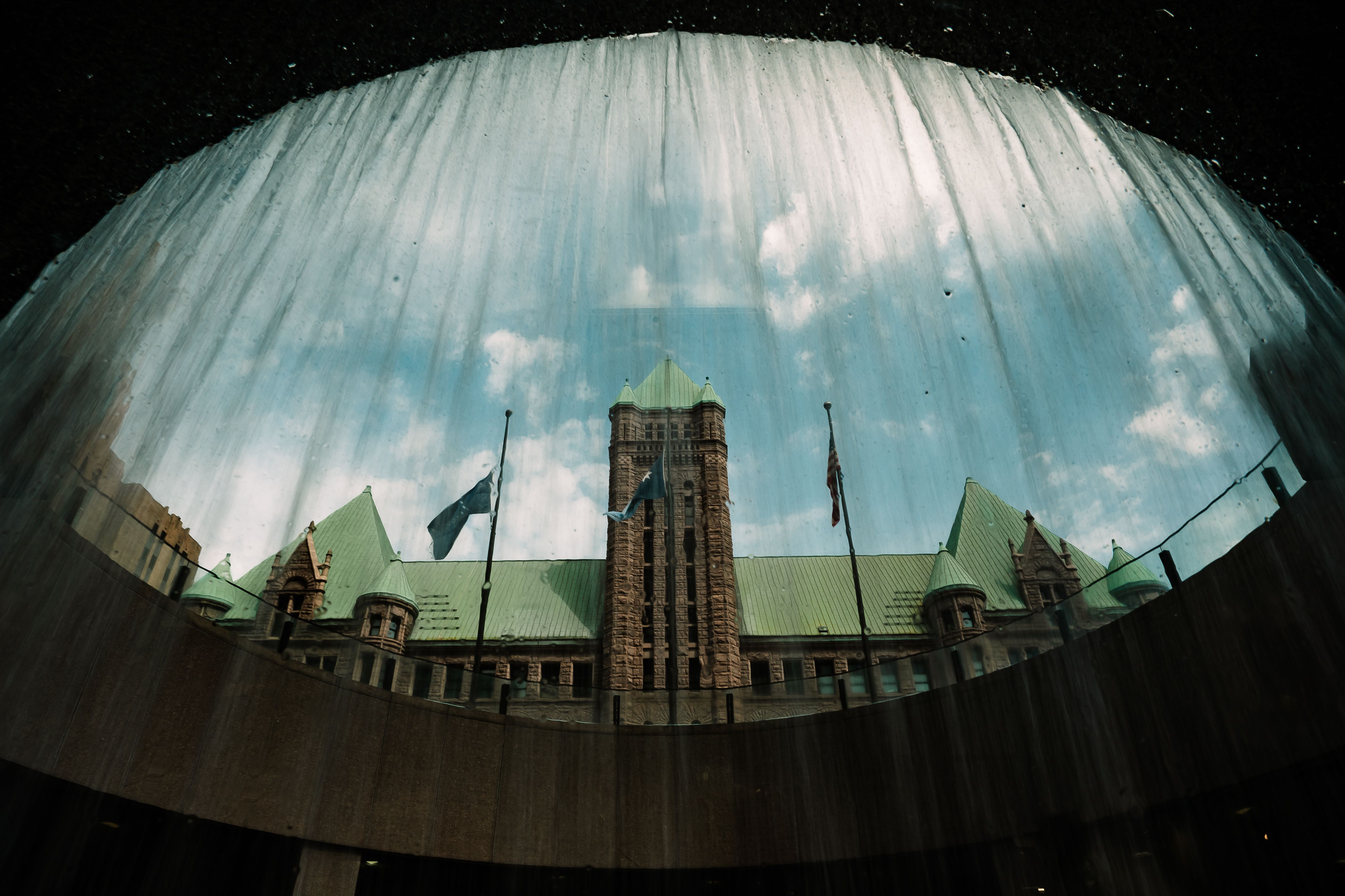 Captivating view of Minneapolis City Hall from underneath a waterfall, showcasing its architectural beauty.